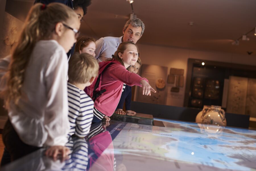 Kinder besuchen ein Museum und betrachten eine digitale Landkarte - Exkursion im Museum